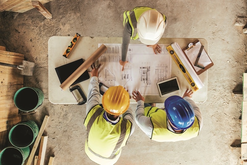 Top view, construction workers or blueprint planning in house, home or office building in real estate, property or architecture innovation. Men, engineering woman or construction site people or ideas, construction site